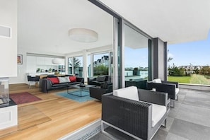A modern living space with a sofa, coffee table, and wicker chairs. - Holiday apartment with 1 bedroom (Olpenitz)