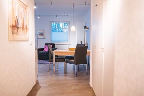 Ein modernes Interieur mit Essbereich, einer Couch und einem Fenster mit Jalousien.