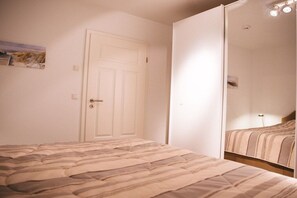 Une chambre à coucher avec un lit, une porte et un miroir qui reflète le lit.