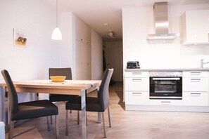 Eine moderne Küche mit weißen Schränken, einem Einbauofen und einem Essbereich mit Tisch und Stühlen.