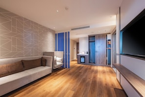 Una sala moderna con un sofá, una televisión y una cocina al fondo.