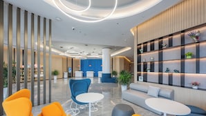 A modern lobby with seating areas, a reception desk, and decorative shelves. - Holiday Inn Express Huludao Seaview an IHG Hotel (Huludao)