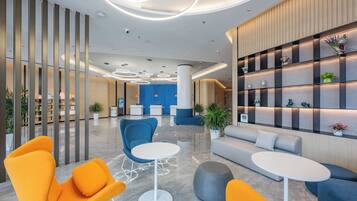 Eine moderne Lobby mit Sitzbereichen, einem Empfangstisch und dekorativen Regalen.