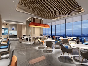 Un comedor moderno con mesas y sillas, un ventanal con vista a la ciudad y un diseño de techo original.