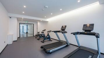Ein Fitnessstudio mit Laufbändern, Ergometer und einem an der Wand montierten Bildschirm.