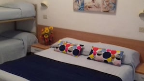 Un dormitorio con cama, almohadas, mesita de noche, lámpara y decoración en la pared.