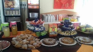 Una mesa de buffet con diversos alimentos, como pasteles, frutas y salsas.