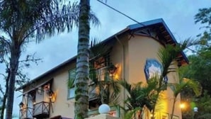 Un bâtiment à deux étages, doté d’un pilier en pierre, avec une voiture garée devant et un balcon muni d’une balustrade.