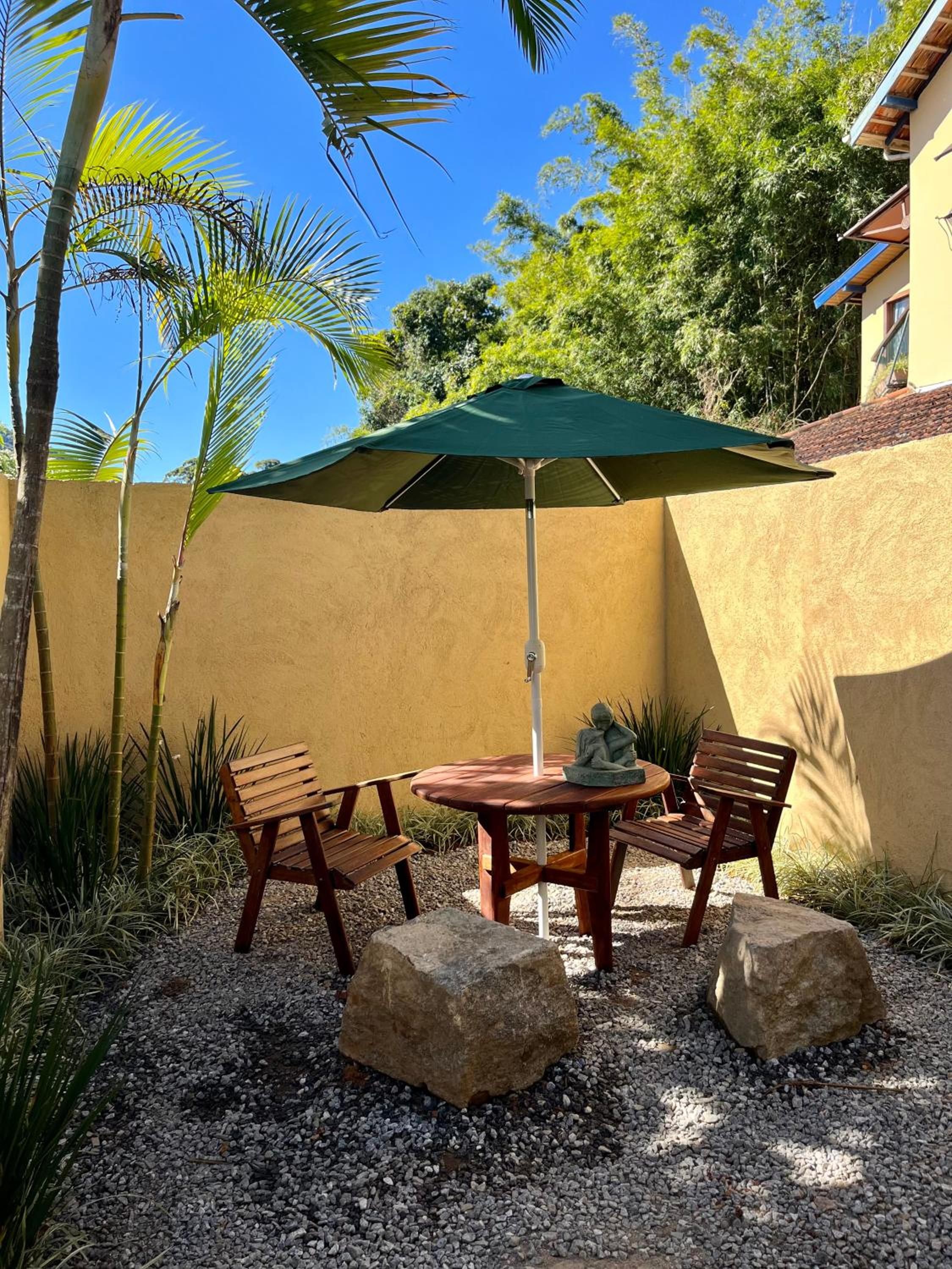 An outdoor seating area with a table and chairs, an umbrella, and decorative statues.