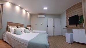 A bedroom with two beds, a TV, a small fridge, and an air conditioning unit. - Pureza Hotel (Timon)