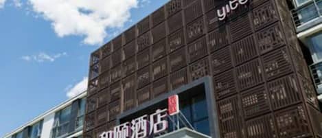 A hotel building with a modern facade, signage indicating it is a hotel, and a clear sky in the background.