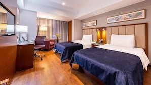 Ett hotellrum med två sängar, ett skrivbord, en stol och ett stort fönster.