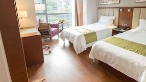 Ett hotellrum med två sängar, ett skrivbord, en stol och ett fönster med utsikt.