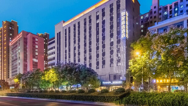 Ein mehrstöckiges Hotel mit modernem Design, das einen markanten Eingang und eine gut beleuchtete Fassade hat.