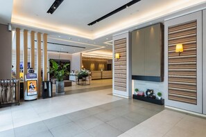 A modern hotel lobby with a reception desk, a self-service kiosk, and a seating area with a plant. - Homeinn Plus (Changzhou)
