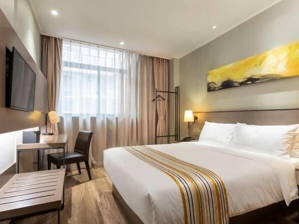 A hotel room with a bed, desk, chair, and a TV mounted on the wall. - Homeinn Plus (Changzhou)