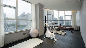 Ein modernes Fitnessstudio mit Trainingsgeräten, großen Fenstern und Blick auf die Stadt.