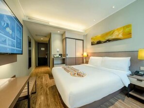 Une chambre d’hôtel avec un grand lit, un bureau, une chaise, une télévision et un tableau au mur.