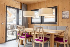 A wooden interior with a dining table and chairs, large windows, and a view of the outside. - Cabin with 1 bedroom (St. Georgen am Kreischberg)