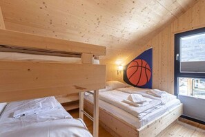 Ein Zimmer in einer Holzhütte mit Etagenbetten, einer Wanddekoration zum Thema Basketball und einem Fenster mit Blick.