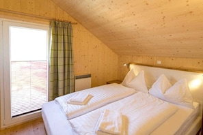 A room with a bed, a window with curtains, and a wooden ceiling. - Cabin with 1 bedroom (St. Georgen am Kreischberg)