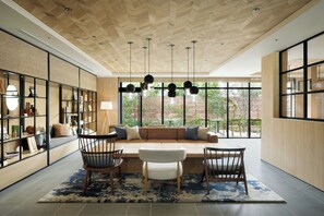 Un interior moderno con techo de madera, una zona de estar con sofá y sillones, y un ventanal que ofrece vistas al verdor.