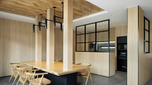 Una cucina moderna con isola centrale, sedie in legno e piano di lavoro nero.
