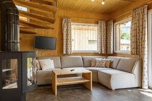 Un accogliente soggiorno con un divano componibile, un tavolino in legno, un caminetto e un televisore fissato alla parete.