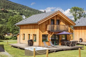 A wooden cabin with a balcony, outdoor seating, and a hot tub. - Cabin with 1 bedroom (St. Georgen am Kreischberg)