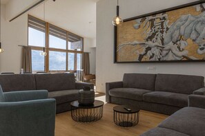A modern living room with grey sofas, round coffee tables, and a large abstract painting on the wall. - Penthouse with 5 bedrooms (Mittersill)