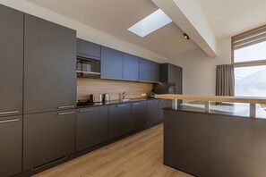 A modern kitchen with dark cabinetry, a wooden countertop, and a skylight. - Penthouse with 5 bedrooms (Mittersill)