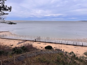 En strand med en træpromenade, der fører til et indhegnet område.