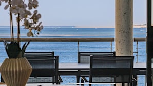 A dining area with a view of the ocean, featuring a table with chairs and a vase of flowers. - Villa Pyla - Côte d'Azur, 7-bedroom villa with private beach access (La Teste-de-Buch)