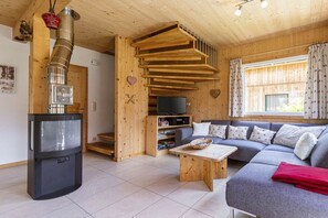 Ein gemütliches Wohnzimmer mit Kamin, einer Couch, einem Fernseher und einer Holztreppe.