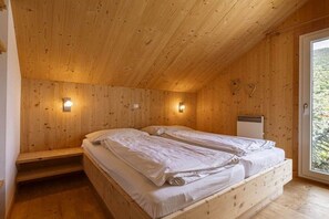 A wooden cabin bedroom with two beds, a bench, and a window. - Cabin with 1 bedroom (St. Georgen am Kreischberg)