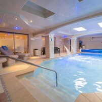 Ein Innenpool mit Liegebereich, einer Rutsche und einer Sauna.