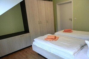 Ein Schlafzimmer mit zwei Betten, einem Kleiderschrank und einer Tür.