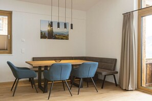 Ein Essbereich mit Holztisch, vier Stühlen, einer Bank und einem Bild an der Wand.