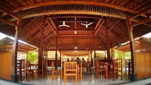 A covered pavilion with a wooden roof, several wooden chairs, and a central table. - Grand Cepu Hotel (Cepu)