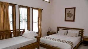 A double bed with a wooden frame and white bedding, a bedside table with a lamp, and a window with curtains. - Grand Cepu Hotel (Cepu)