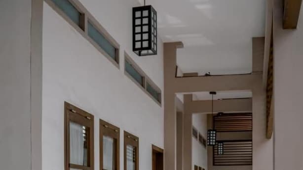 A corridor with wooden furniture and a hanging light fixture. - Grand Cepu Hotel (Cepu)