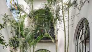 En gårdhave med plantekasser, udendørs siddepladser og fliset gulv.