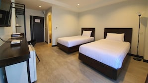 Habitación de hotel con dos camas, un escritorio, una silla y un televisor.