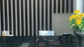 A reception area with a black and white striped wall, a reception desk, and a potted plant with yellow flowers.
