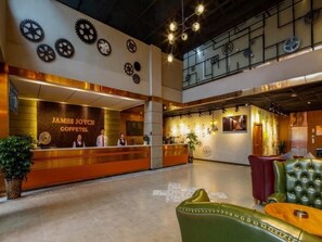 A hotel lobby with a reception desk, seating area, and decorative wall elements. - James Joyce Coffetel (Chengdu)