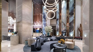 A modern lobby with a curved seating area, a reception desk, and a decorative light fixture. - New Century Hotel Binjiang Hangzhou (Hangzhou)