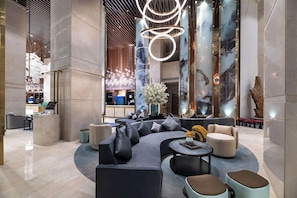 A modern lobby with a curved seating area, a reception desk, and a decorative light fixture. - New Century Hotel Binjiang Hangzhou (Hangzhou)
