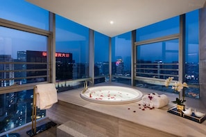 A modern bathroom with a large bathtub, city views, and a towel rack. - New Century Hotel Binjiang Hangzhou (Hangzhou)