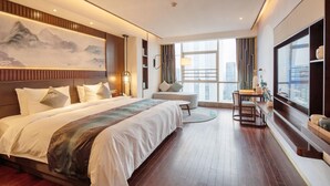 A modern hotel room with a large bed, a desk, and a view of the city. - New Century Hotel Binjiang Hangzhou (Hangzhou)
