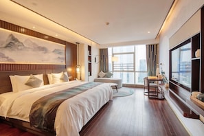 A modern hotel room with a large bed, a desk, and a view of the city. - New Century Hotel Binjiang Hangzhou (Hangzhou)